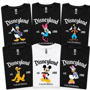 Op de afbeelding: Collectie zwarte en witte t-shirts met Disneyland-personages. Elk shirt toont "Disneyland", "est. 1955 CALIFORNIA", en een ander personage: Donald Duck, Minnie Mouse, Goofy, Pluto, Mickey Mouse en Katrien Duck.