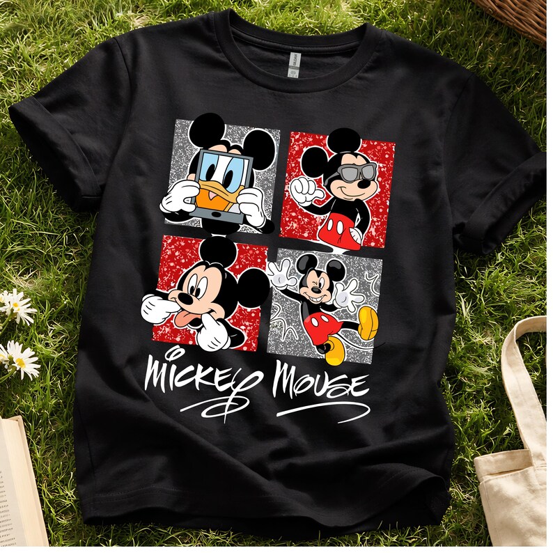 Op de afbeelding: Zwart T-shirt met vier panelen met Mickey Mouse in verschillende poses. De panelen hebben rode en zilveren glitterachtergronden. De woorden "Mickey Mouse" staan eronder in een cursief lettertype.