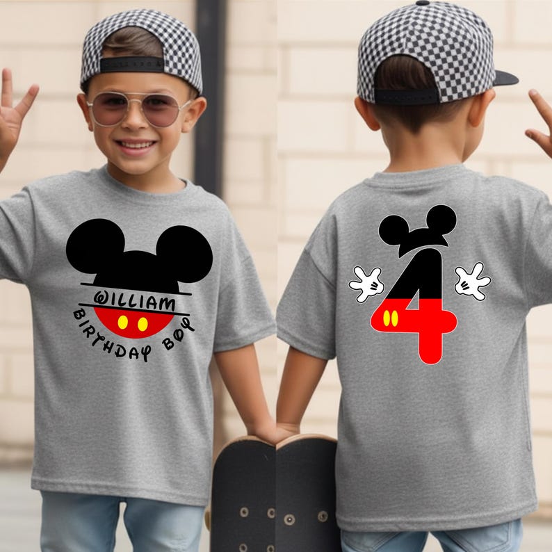 May include: A gray t-shirt featuring a Mickey Mouse design with the name "William" and the words "Birthday Boy." The back of the shirt displays a large number "4" in red and black, with Mickey Mouse gloves.