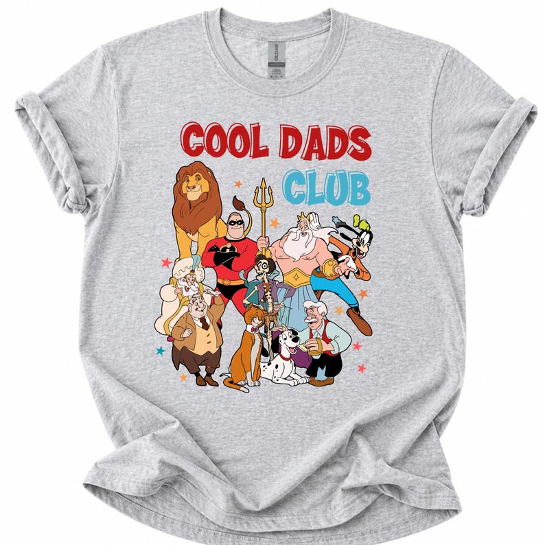 Pode incluir: Camiseta cinza claro com um gr&aacute;fico colorido de personagens de desenhos animados, incluindo um le&atilde;o e um super-her&oacute;i. O texto "COOL DADS CLUB" &eacute; impresso em vermelho e azul acima dos personagens. A camiseta tem mangas curtas e gola redonda.