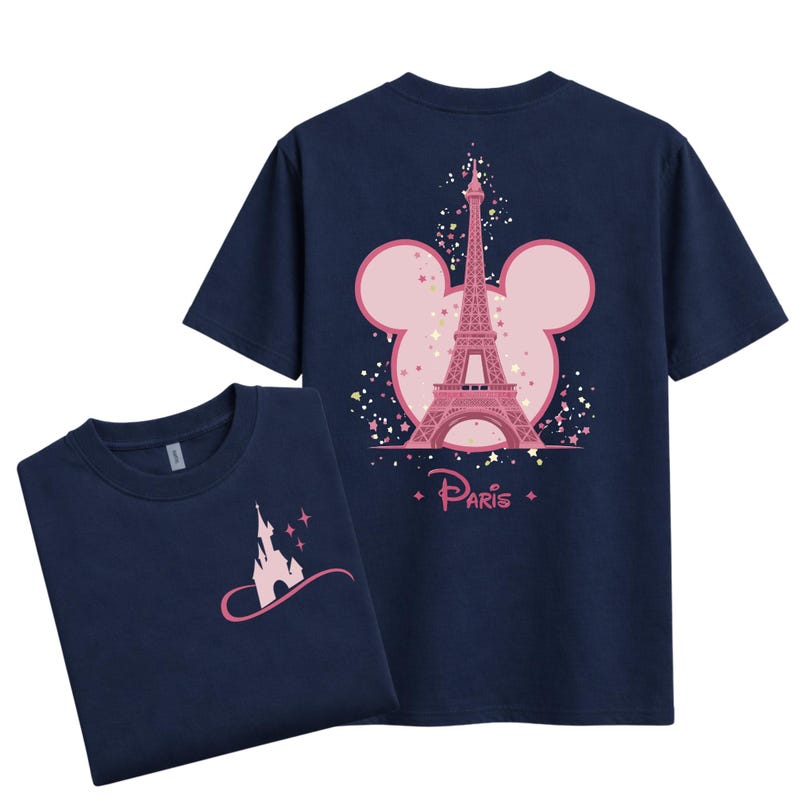 May include: Navy blue t-shirts featuring a pink Eiffel Tower design within a Mickey Mouse silhouette on the back. The front of the shirt displays a pink castle design. The word "Paris" is written below the Eiffel Tower.