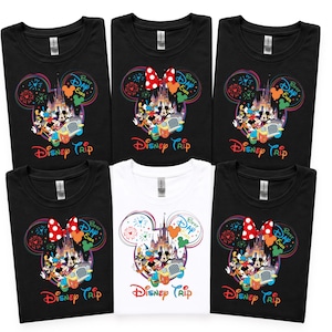 Puede incluir: Seis camisetas, cinco negras y una blanca, con un colorido dise&ntilde;o de Disney Trip. El dise&ntilde;o incluye orejas de Mickey Mouse, fuegos artificiales, un castillo y el texto "Best Day Ever".