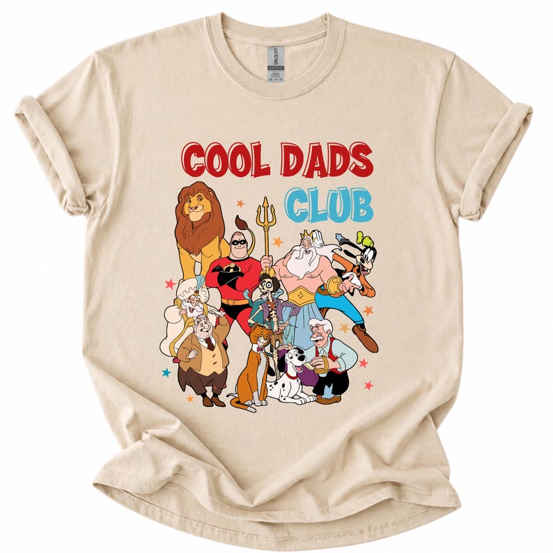 Pode incluir: Camiseta bege com uma estampa de personagens de desenhos animados, incluindo um le&atilde;o, um super-her&oacute;i e um c&atilde;o. O texto "COOL DADS CLUB" &eacute; impresso em vermelho e azul acima dos personagens. A camisa tem as mangas enroladas.