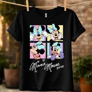 Pu&ograve; includere: T-shirt nera con una grafica a quattro pannelli di Minnie Mouse in varie pose, ciascuna con uno sfondo pastello diverso. La maglietta include il testo "Minnie Mouse xoxo" in corsivo.