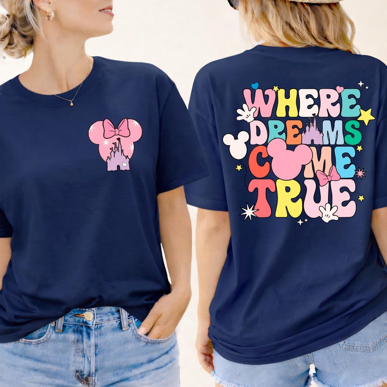 May include: Navy blue t-shirt featuring a pink Minnie Mouse design on the front and the words "WHERE DREAMS COME TRUE" on the back. The design includes a castle, bow, and stars in various colours.