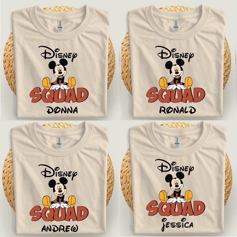 Op de afbeelding: Vier cr&egrave;mekleurige t-shirts met een Mickey Mouse-afbeelding en de tekst "Disney Squad" in het rood, met de namen Donna, Ronald, Andrew en Jessica. De shirts worden gepresenteerd op een geweven oppervlak.
