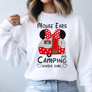Puede incluir: Sudadera blanca con un dise&ntilde;o de caravana roja y blanca con lunares, con orejas de rat&oacute;n y un lazo. El texto dice "Mouse Ears and Camping Kinda Girl."