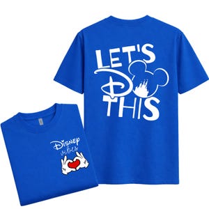 K&ouml;nnte beinhalten: Zwei k&ouml;nigsblaue T-Shirts. Eines zeigt "Disney vibes" mit einer herzf&ouml;rmigen Handgeste. Das andere zeigt "LET'S DO THIS" mit einer Mickey Mouse Silhouette. Beide Shirts sind kurz&auml;rmlig.