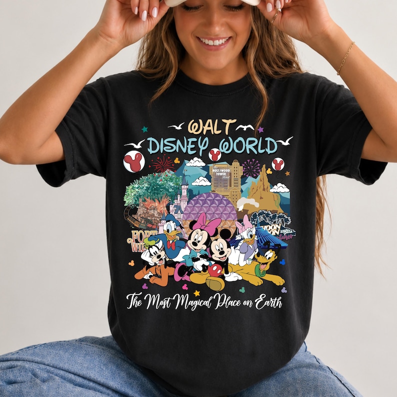 K&ouml;nnte beinhalten: Schwarzes T-Shirt mit einer farbenfrohen Grafik von Disney-Figuren und Wahrzeichen. Das Design zeigt Micky und Minnie Maus, Donald Duck und Goofy, mit dem Text "Walt Disney World" und "The Most Magical Place on Earth."