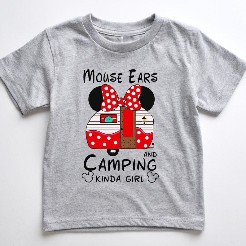 Puede incluir: Una camiseta gris de manga corta con un gr&aacute;fico de una caravana de lunares rojos y blancos, orejas de rat&oacute;n negras y un lazo rojo. El texto dice "Mouse Ears and Camping Kinda Girl."