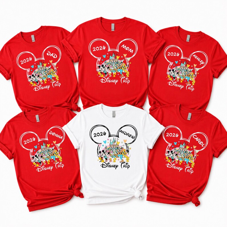 May include: Red and white t-shirts with a Disney theme. Each shirt features a Mickey Mouse head design with the year 2026 and a name, such as "Dad," "Mom," "Donna," "Andrew," "Ashley," and "Carol." The shirts have a colourful Disney castle graphic.