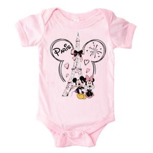 K&ouml;nnte beinhalten: Hellrosa Baby-Body mit einer Grafik von Mickey und Minnie Mouse vor dem Eiffelturm. Das Design enth&auml;lt das Wort "Paris" und Herzformen. Der Body hat kurze &Auml;rmel und einen runden Ausschnitt.