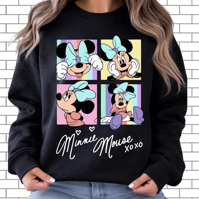 Pu&ograve; includere: Felpa nera con quattro pannelli che mostrano illustrazioni di Minnie Mouse. Ogni pannello mostra una posa diversa di Minnie Mouse con un fiocco azzurro. Le parole "Minnie Mouse xoxo" sono scritte in bianco sotto i pannelli.