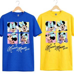 Pu&ograve; includere: Due magliette a maniche corte, una blu e una gialla, ciascuna con una grafica di Minnie Mouse. La grafica mostra Minnie in quattro pose diverse, con un fiocco azzurro e le parole "Minnie Mouse xoxo" in corsivo.