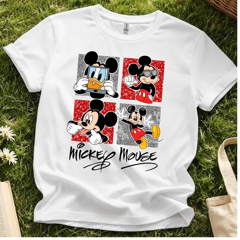Op de afbeelding: Wit T-shirt met een ontwerp van vier panelen met Mickey Mouse in verschillende poses. De panelen wisselen af met rode en zilveren achtergronden. De woorden "Mickey Mouse" staan in een gestileerd lettertype eronder.