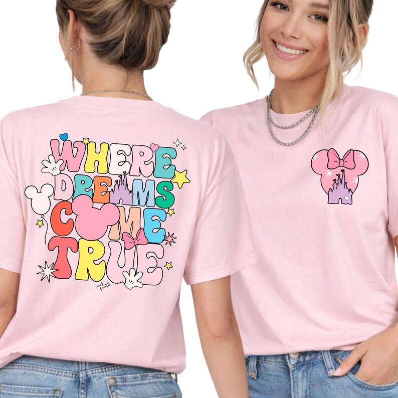 May include: Pale pink t-shirts with a colourful graphic design. One shirt displays the text "WHERE DREAMS COME TRUE" with Mickey Mouse-themed elements. The other shirt has a Minnie Mouse bow and castle design.