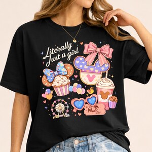 Pode incluir: Camiseta preta com um design gr&aacute;fico colorido com um cupcake, orelhas do Mickey, uma roda gigante, &oacute;culos de sol em forma de cora&ccedil;&atilde;o e uma bebida. O texto "Literally Just a girl" est&aacute; escrito em it&aacute;lico.