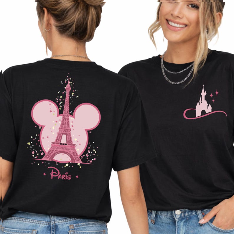 May include: Black t-shirts with pink graphics. One shirt features the Eiffel Tower inside a Mickey Mouse head outline with the word "Paris". The other shirt has a castle graphic with stars.