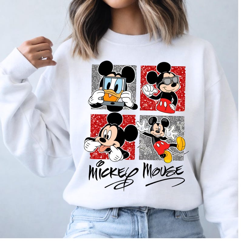 Op de afbeelding: Witte sweatshirt met een Mickey Mouse-ontwerp. Het ontwerp bevat vier panelen met verschillende Mickey Mouse-poses, tegen rode en grijze glitterachtergronden. De woorden "Mickey Mouse" zijn geschreven in een gestileerd lettertype.