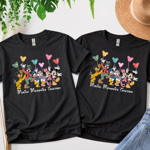 May include: Two black t-shirts with a colorful graphic of Disney characters holding balloons. The graphic includes Mickey Mouse, Minnie Mouse, Donald Duck, and Goofy. The text "Making Memories Together" is written below the characters.