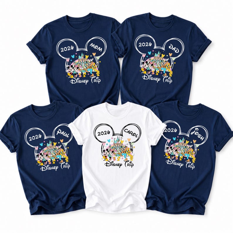 May include: Five navy blue and white t-shirts with a Disney theme. Each shirt features a Mickey Mouse head outline with the year "2026" and the names "Mom", "Dad", "Paul", "Carol", and "Josh". The shirts have a colourful Disney castle and character design.