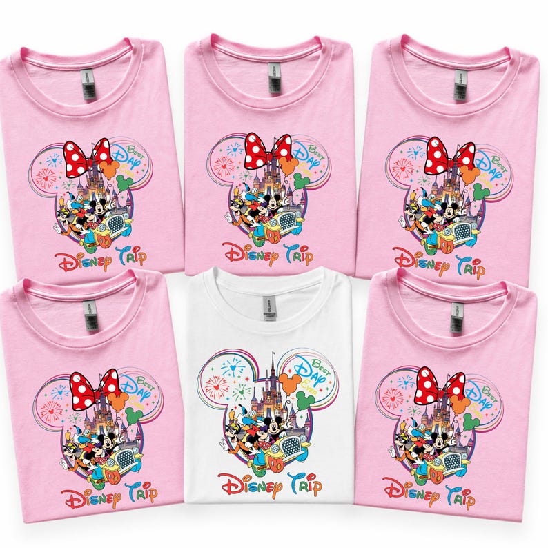 Puede incluir: Camisetas rosas y blancas con un dise&ntilde;o de Disney Trip. El dise&ntilde;o presenta a Mickey y Minnie Mouse, un castillo y la frase "Best Day Ever". Las camisetas tienen cuello redondo y mangas cortas.