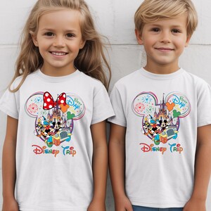 Puede incluir: Camisetas blancas con un dise&ntilde;o colorido de Disney Trip. El dise&ntilde;o incluye Mickey y Minnie Mouse, un castillo, fuegos artificiales y el texto "Best Day" y "Disney Trip".