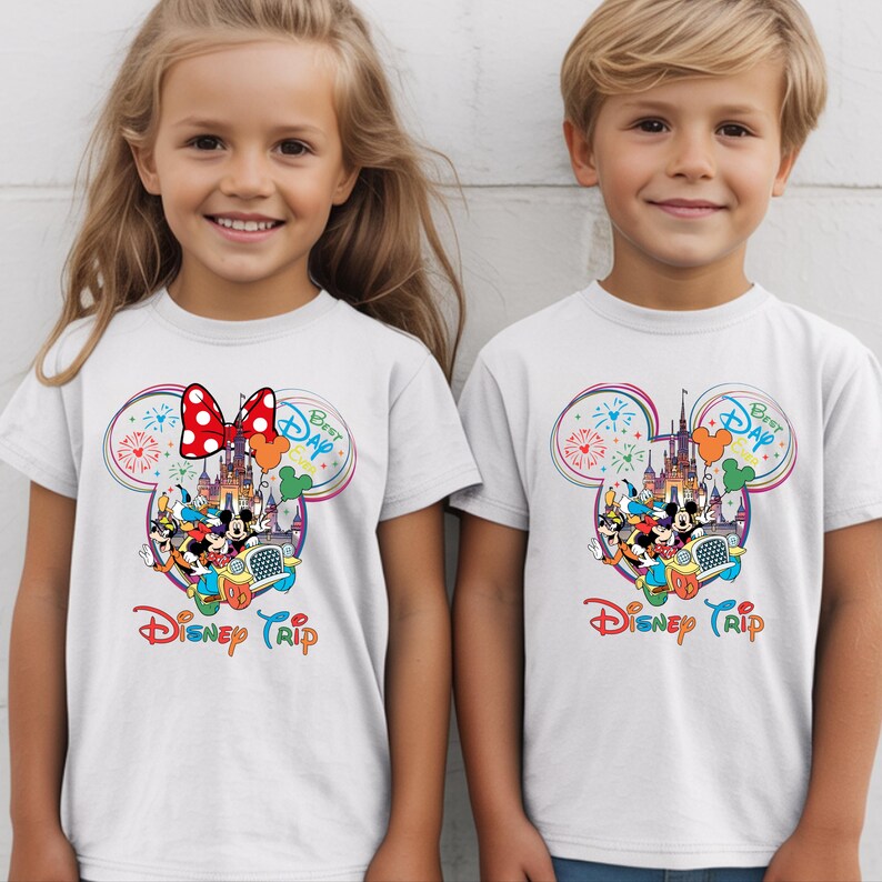 Puede incluir: Camisetas blancas con un dise&ntilde;o colorido de Disney Trip. El dise&ntilde;o incluye Mickey y Minnie Mouse, un castillo, fuegos artificiales y el texto "Best Day" y "Disney Trip".