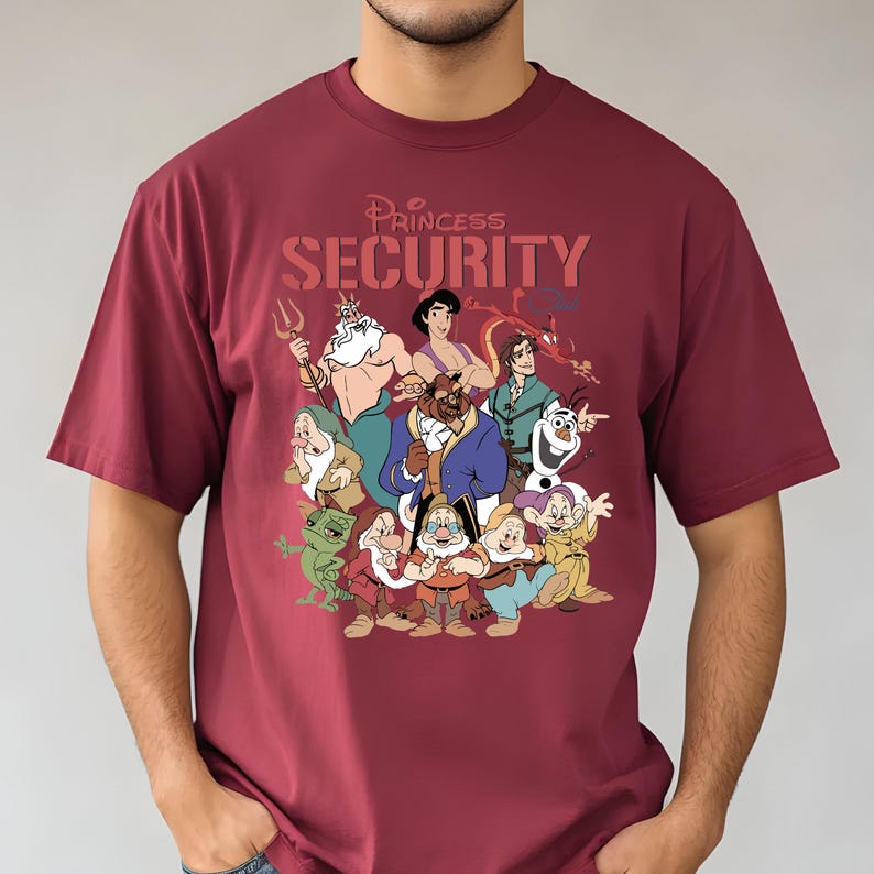 May include: Burgundy t-shirt with a graphic of Disney characters and the text "Princess Security". The design includes characters such as Ariel, Aladdin, and the Beast. The shirt is made of a soft material.
