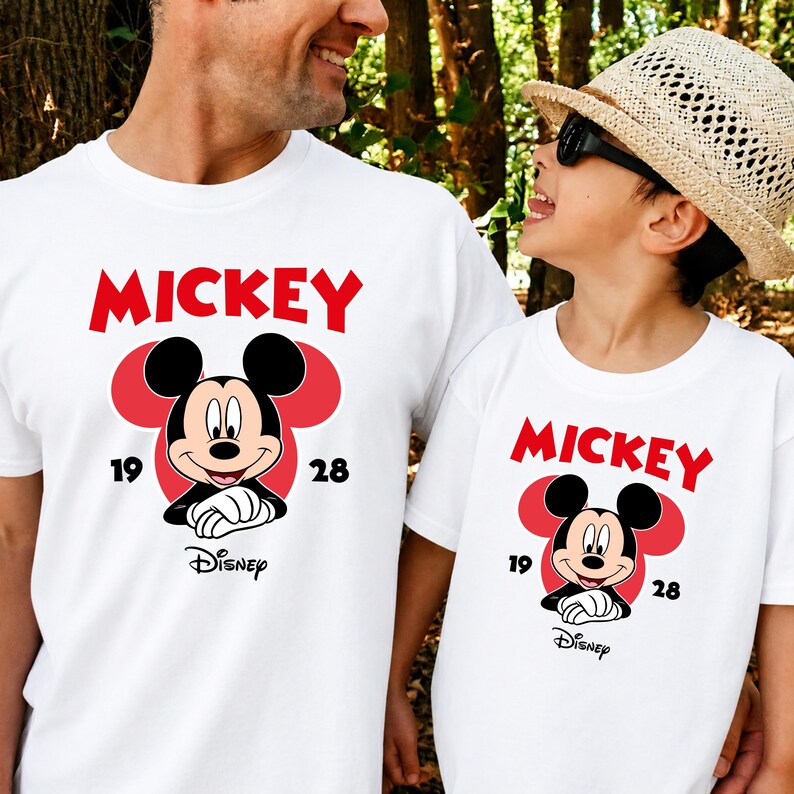 May include: White t-shirts with a Mickey Mouse graphic. The design features the word "MICKEY" in red, a cartoon Mickey Mouse, and the numbers "19" and "28". The Disney logo is also present.
