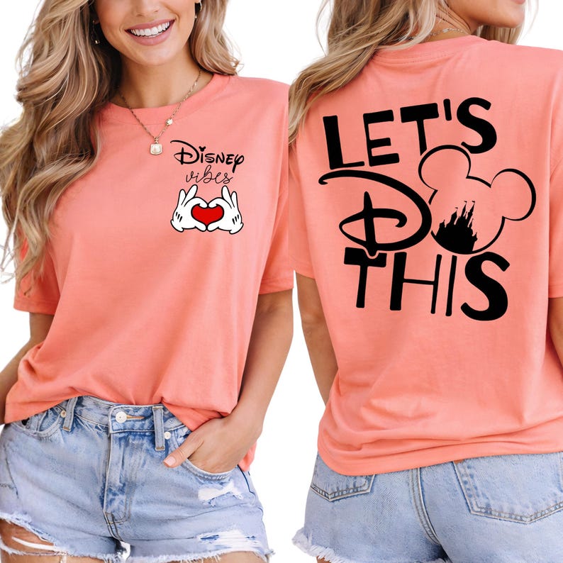 K&ouml;nnte beinhalten: Korallfarbenes T-Shirt mit dem Text "Disney vibes" und einem herzf&ouml;rmigen Handgesten-Motiv auf der Vorderseite. Auf der R&uuml;ckseite steht "LET'S DO THIS" mit einer Mickey Mouse Silhouette. Dazu Jeansshorts.