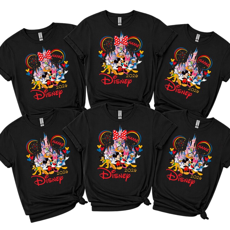 Op de afbeelding: Zes zwarte t-shirts met een kleurrijke Disney-afbeelding. Het ontwerp bevat Mickey en Minnie Mouse, een kasteel en het woord "Disney" in het rood. Het jaar "2026" staat ook op de shirts.