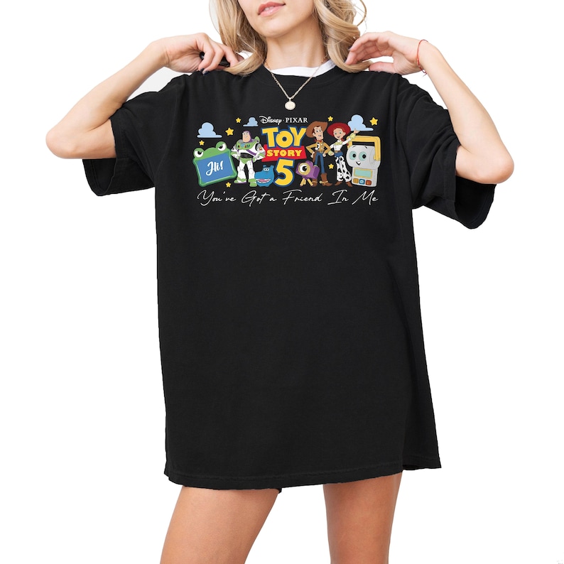 Puede incluir: Una camiseta negra de manga corta con un estampado gr&aacute;fico de los personajes de Disney Pixar Toy Story 5, incluyendo a Buzz Lightyear, Woody y Jessie. El texto dice Toy Story 5 y You've Got a Friend In Me con peque&ntilde;as estrellas amarillas.