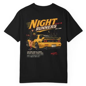Puede incluir: Camiseta negra con un gráfico de un coche deportivo amarillo y el texto "NIGHT RUNNERS" y "EST. 1998". El diseño incluye una persona y texto japonés. También está presente la frase "LIVE FAST. RUN ALL NIGHT. ROTARY HEART. STREET SOUL".