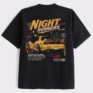 Puede incluir: Camiseta negra con un gráfico de coche deportivo amarillo, el texto "NIGHT RUNNERS" y "EST. 1998". El diseño incluye una mujer, un horizonte urbano y texto japonés. La camiseta también tiene el texto "LIVE FAST. RUN ALL NIGHT. ROTARY HEART. STREET SOUL."