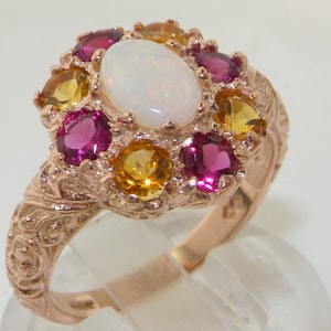 Può includere: Un anello in oro rosa con una pietra centrale di opale bianco circondata da pietre preziose rosa e gialle.