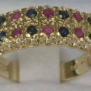 May include: A gold band ring with alternating red and blue gemstones. The ring has a delicate, intricate design.