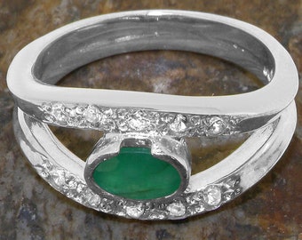 May include: A silver ring with a green oval gemstone and a row of small clear gemstones around the band.