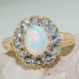 May include: A gold ring with a white opal gemstone surrounded by a halo of blue topaz stones.