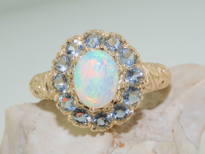 May include: A gold ring with a white opal gemstone surrounded by a halo of blue topaz stones.