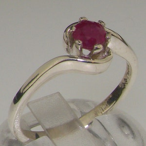 May include: A silver ring with a red ruby gemstone. The ring has a twisted band.