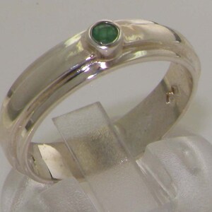 May include: A silver ring with a single green gemstone set in a bezel setting. The ring has a simple, modern design with a slightly rounded band.