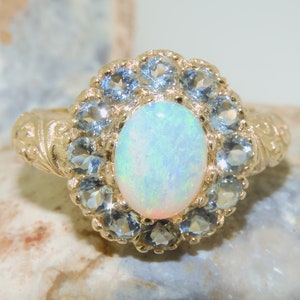 May include: A gold ring with a large white opal surrounded by a halo of smaller blue gemstones.