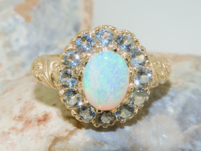 May include: A gold ring with a large white opal surrounded by a halo of smaller blue gemstones.