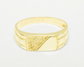 May include: A gold signet ring with a rectangular top and a small row of clear stones. The band of the ring has a textured design.