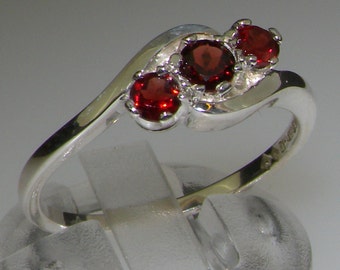 May include: A silver ring with three red gemstones set in a curved design.