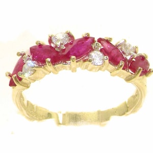 May include: A gold band ring with a cluster of red ruby and white diamond gemstones. The ring is set with marquise and round cut stones.