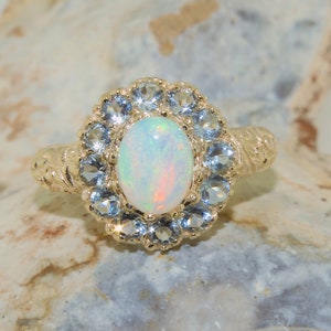 May include: A gold ring with a white opal gemstone surrounded by a halo of blue topaz stones.