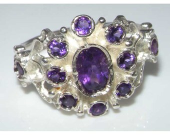 May include: A silver ring featuring a cluster of purple amethyst gemstones. The ring has a delicate, organic design with a large oval-shaped amethyst at the centre.