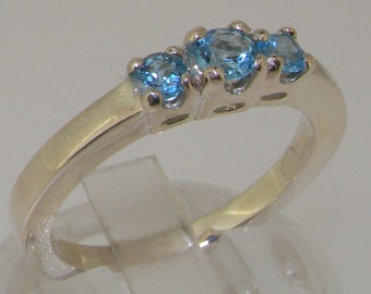 May include: A silver ring with three blue topaz gemstones. The ring is set in a simple band and the stones are arranged in a row.